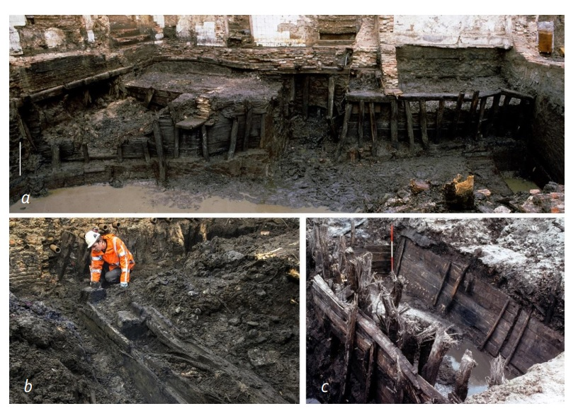 Foto waarop opgravingen van middeleeuwse houten beschoeiingen aan de Prins Hendrikkade en het Waterlooplein zichtbaar zijn.