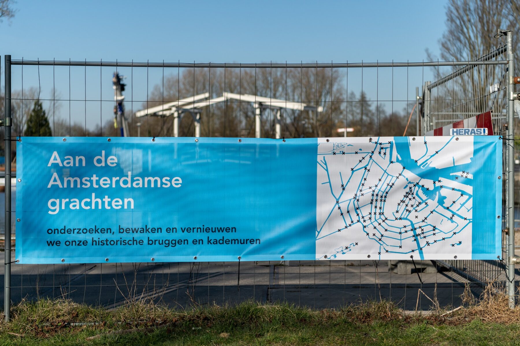 Doek met opschrift over de opdracht van Amsterdam om de historische kademuren te onderzoeken, bewaken en vernieuwen