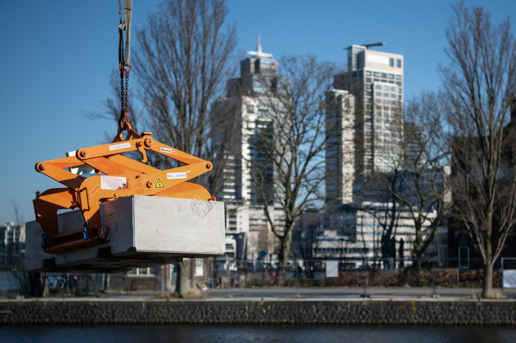 Betonblok zweeft boven het water van insteekhaven met de Amsteltoren en Rembrandttoren op de achtergrond