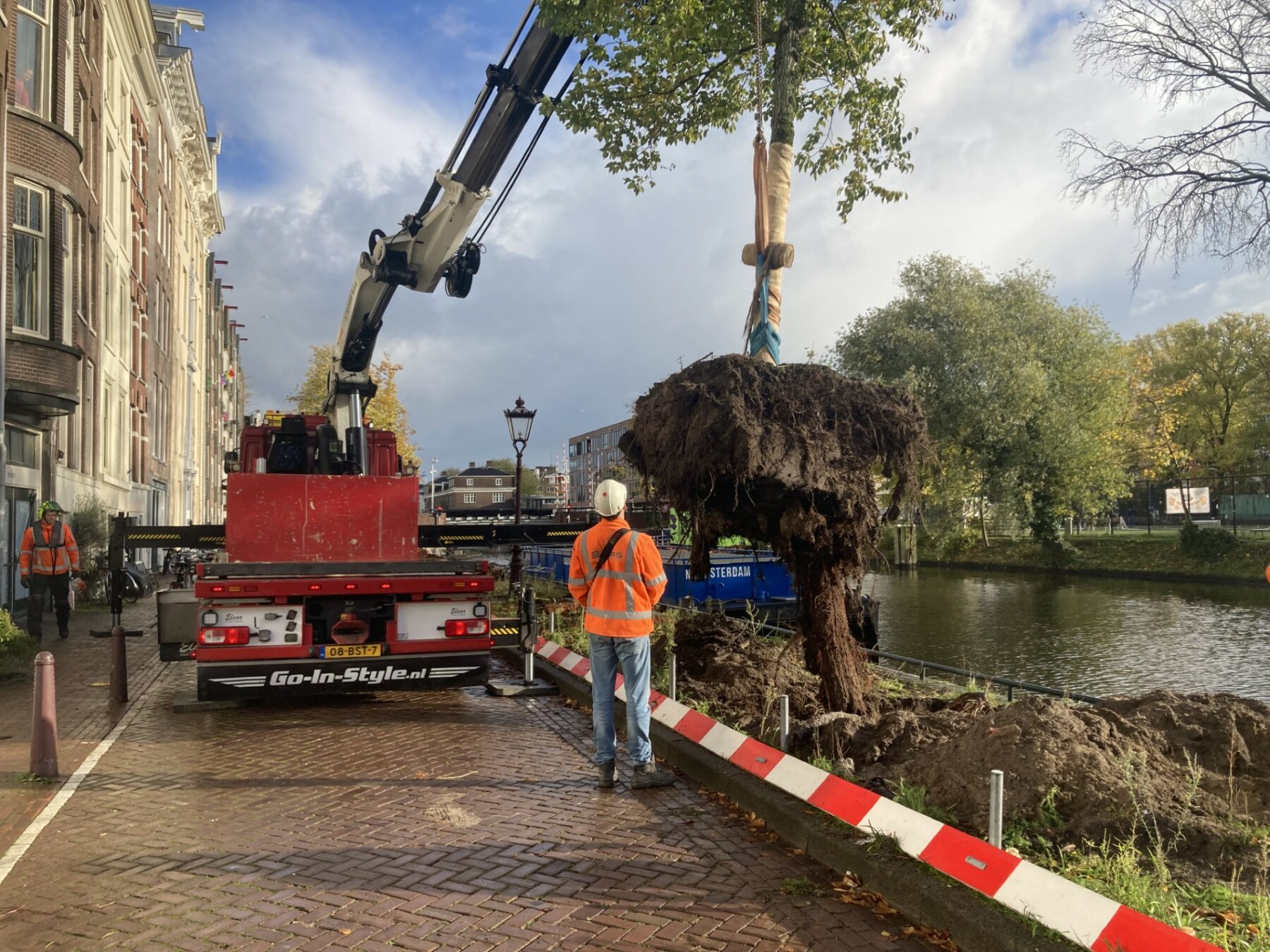 Man hijst boom van zijn plek met kraan aan Nieuwe Herengracht