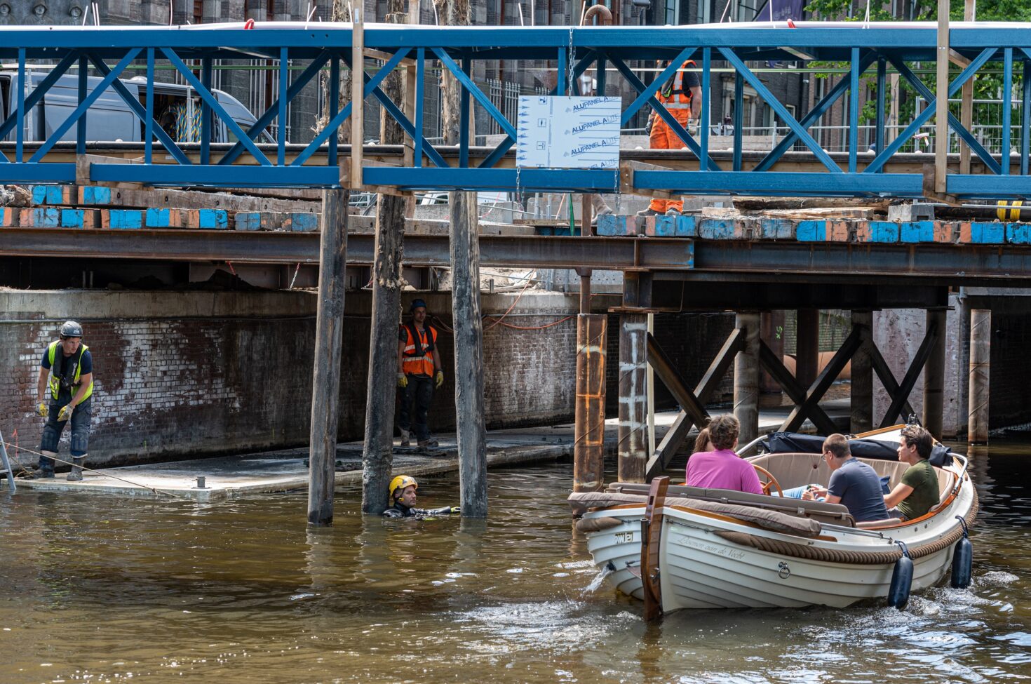 Bootje met toeristen vaart langs duiker, palen en werkzaamheden onder Isa van Eeghenbrug door