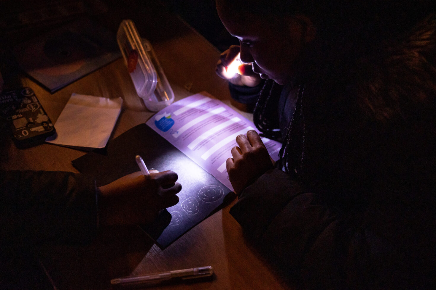 Met een neonpen maken kinderen licht aan boord om een opdracht te maken in hun werkboek
