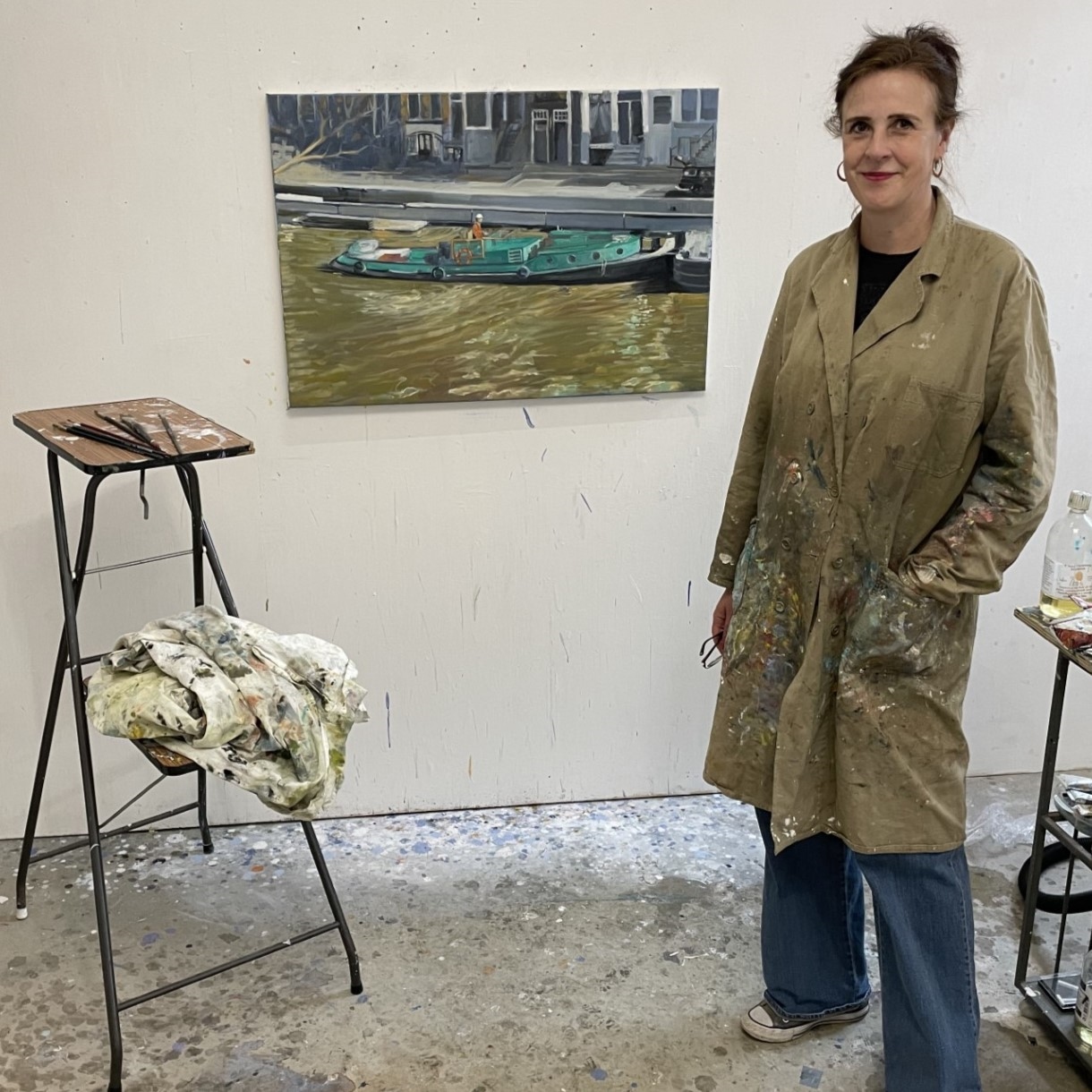 Foto van kunstenaar Carlien Oudes met een van haar schilderijen in haar atelier
