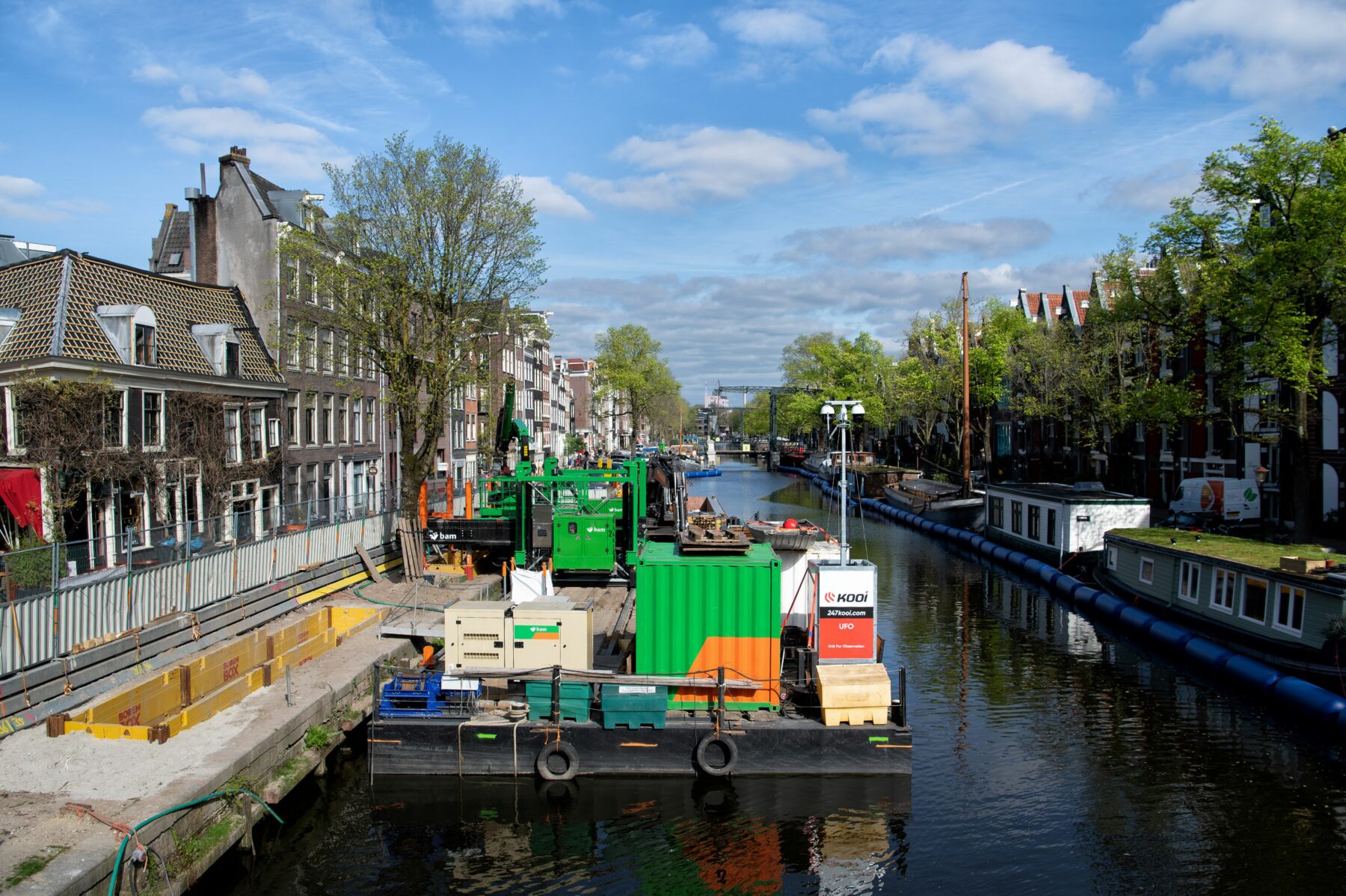 Zicht op de Brouwersgracht met links het bouwterrein op pontons van Koningsgracht en rechts een rij woonboten afgeschermd door een ballenlijn