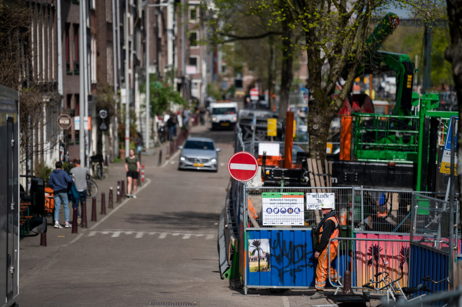 Kade aan de Brouwersgracht met auto's, wandelaars en aan de kant het werkterrein van Koningsgracht. De hekken steken iets uit maar de rijbaan blijft vrij voor het verkeer.