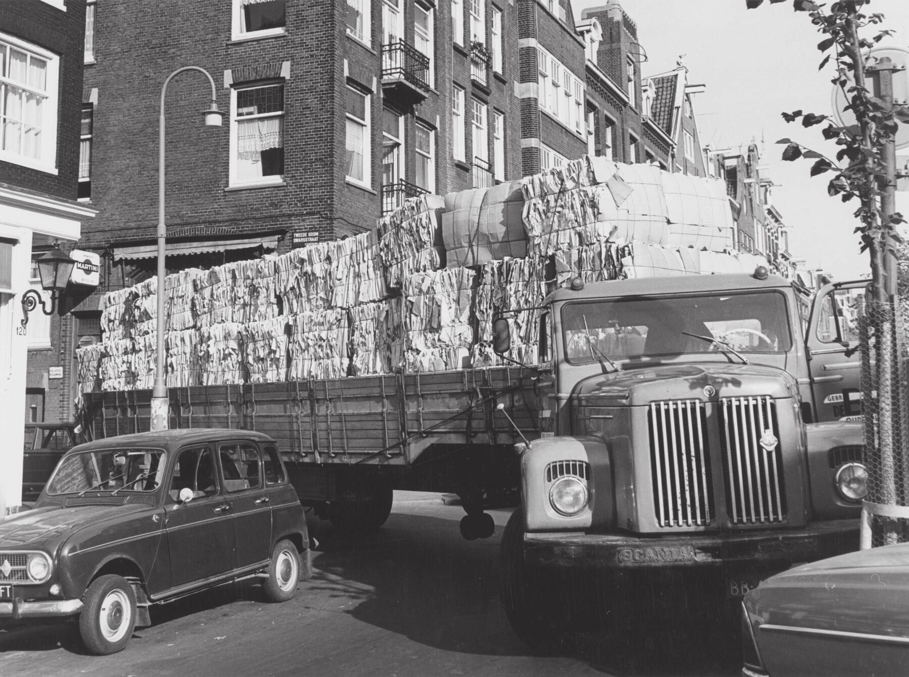 Een vrachtwagen met een papierlading in een nauwe bocht in de Jordaan