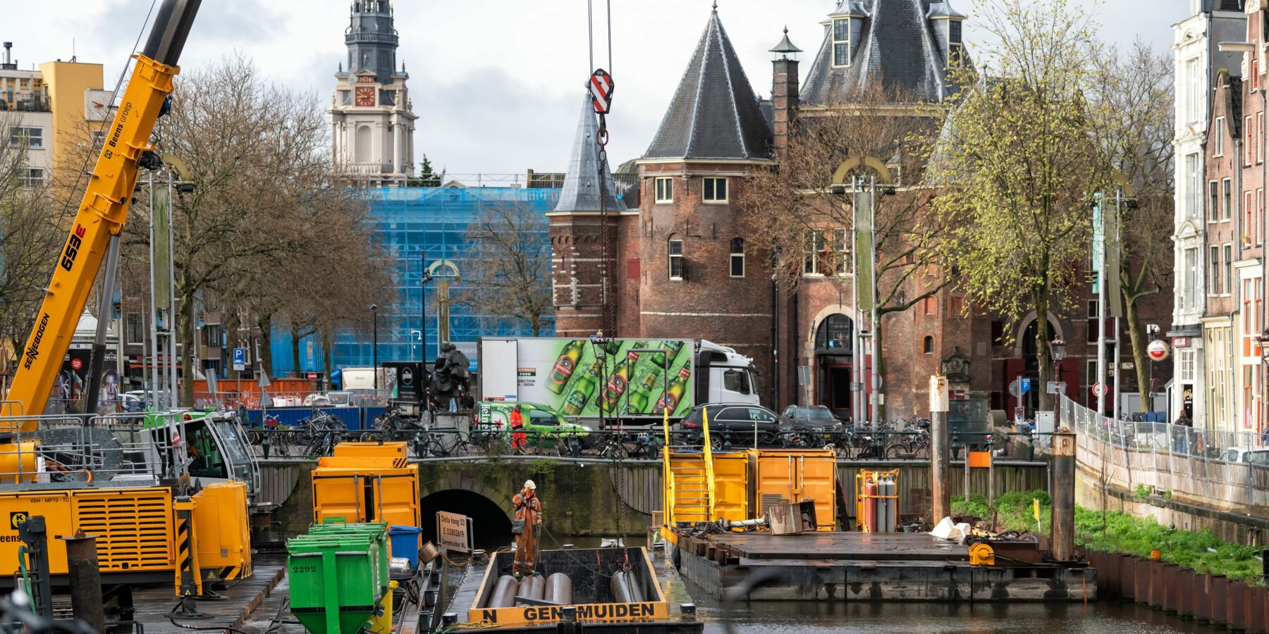 Kadewerkzaamheden bij de Nieuwmarkt. Op de voorgrond schuiten en een kraan, op de achtergrond de Waag en de Zuiderkerk.