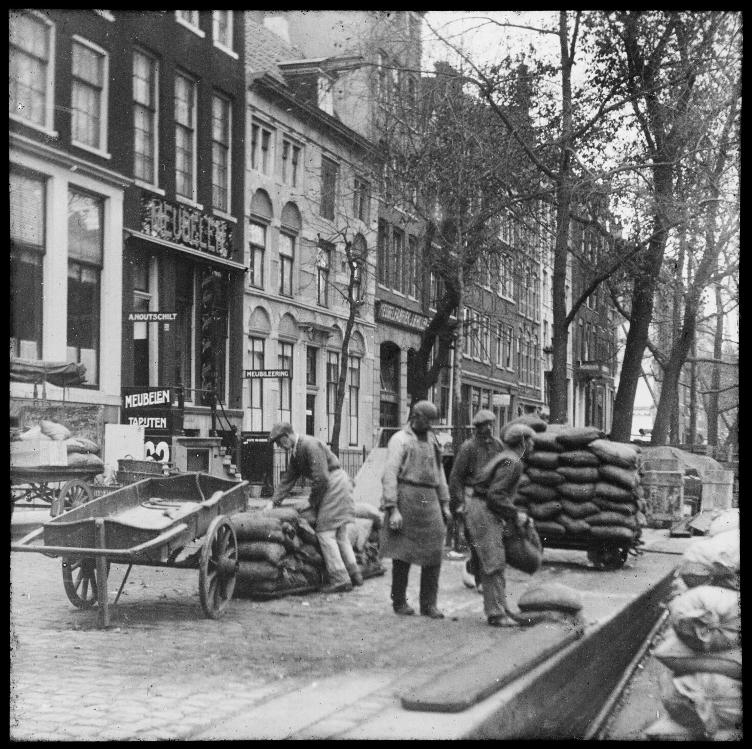 Oude foto van arbeiders die een dekschuit lossen op het Singel, omstreeks 1915