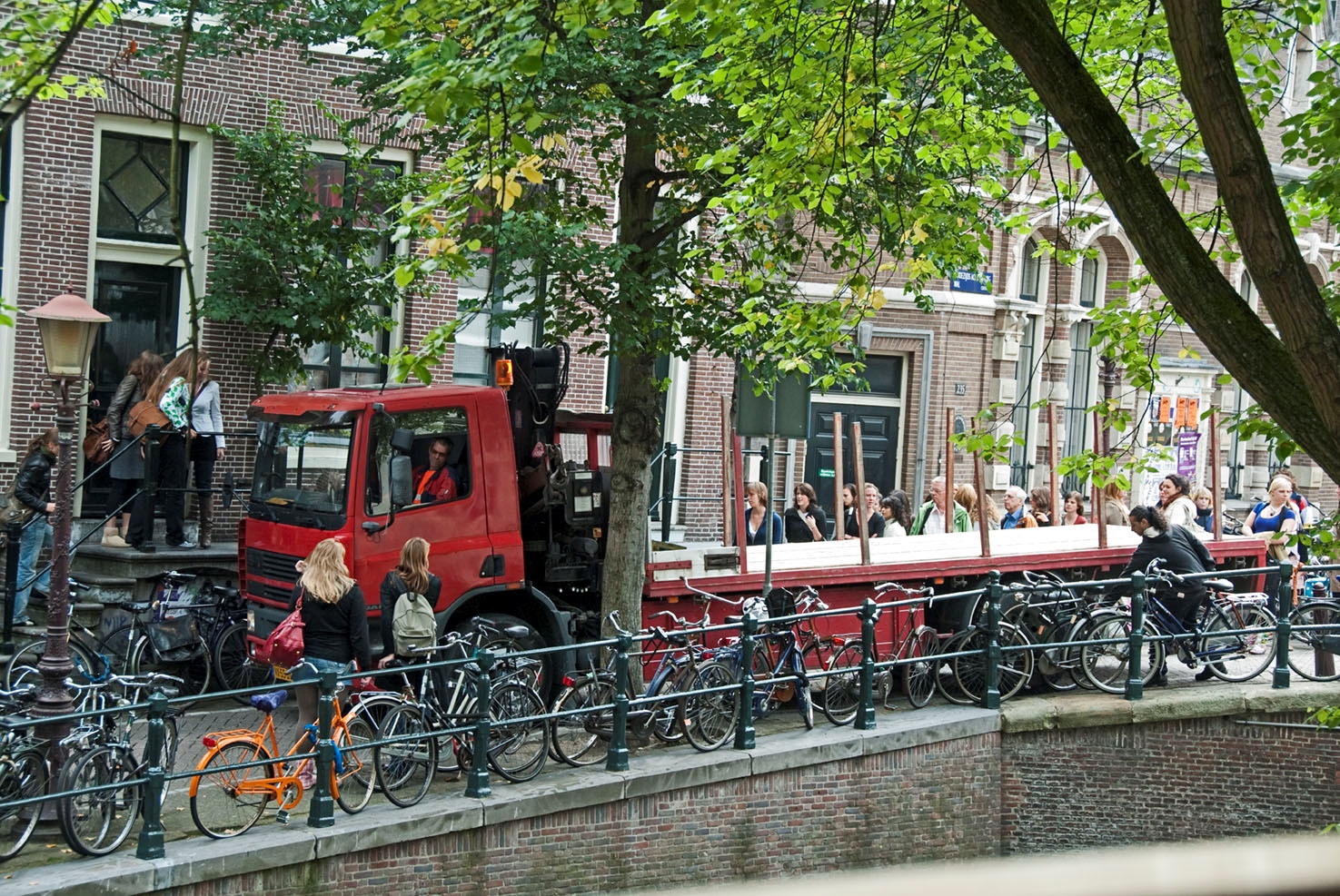 Een lange truck met oplegger probeert de bocht te maken op een kade aan de gracht