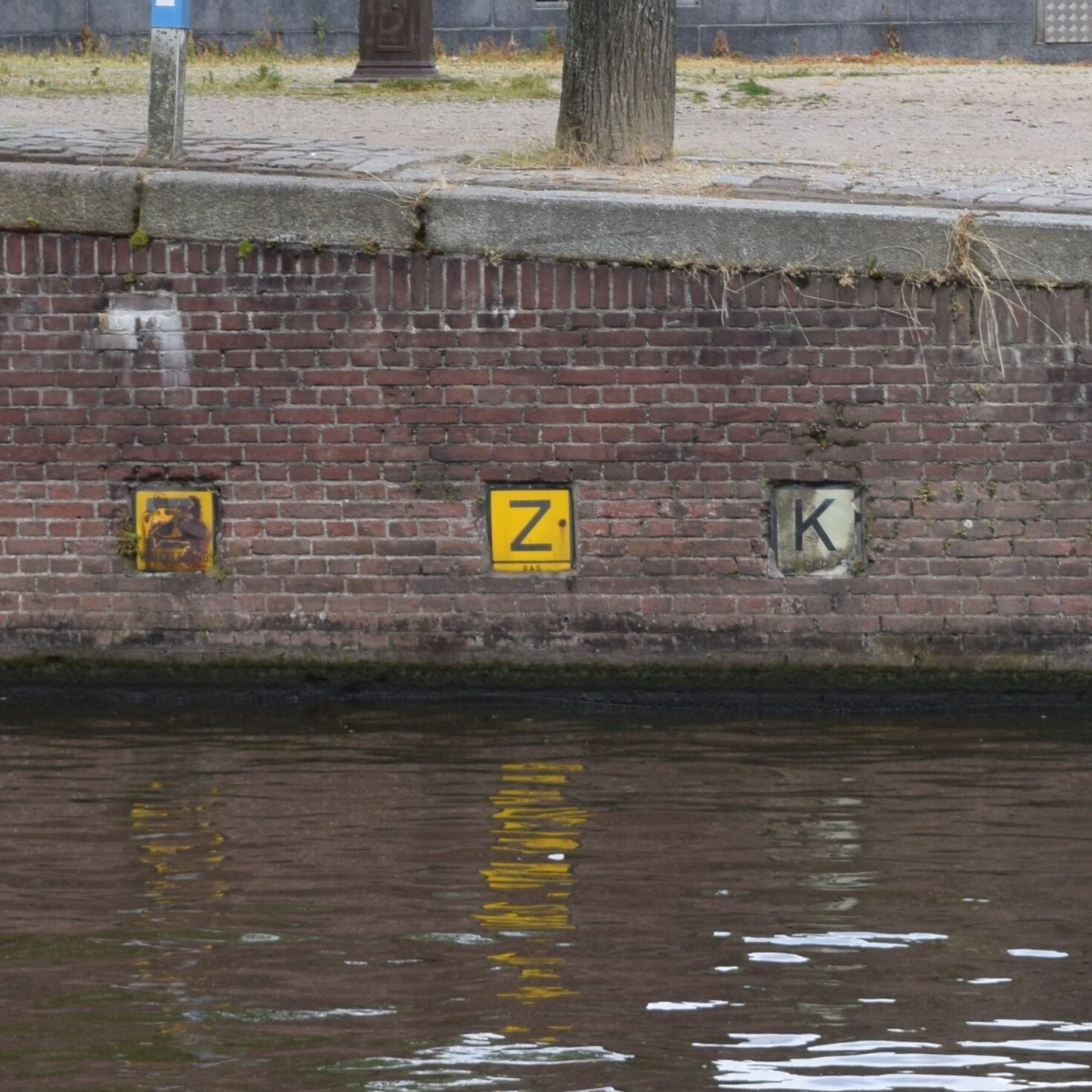 Kademuur met twee zinkerbordjes en een kabelbordje