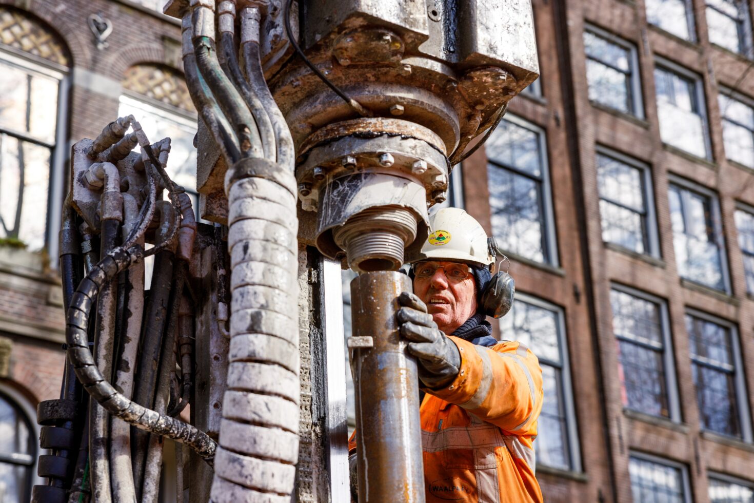 Werker bedient de machine waarmee we de palen in de grond boren en het groutmengsel in de palen spuiten