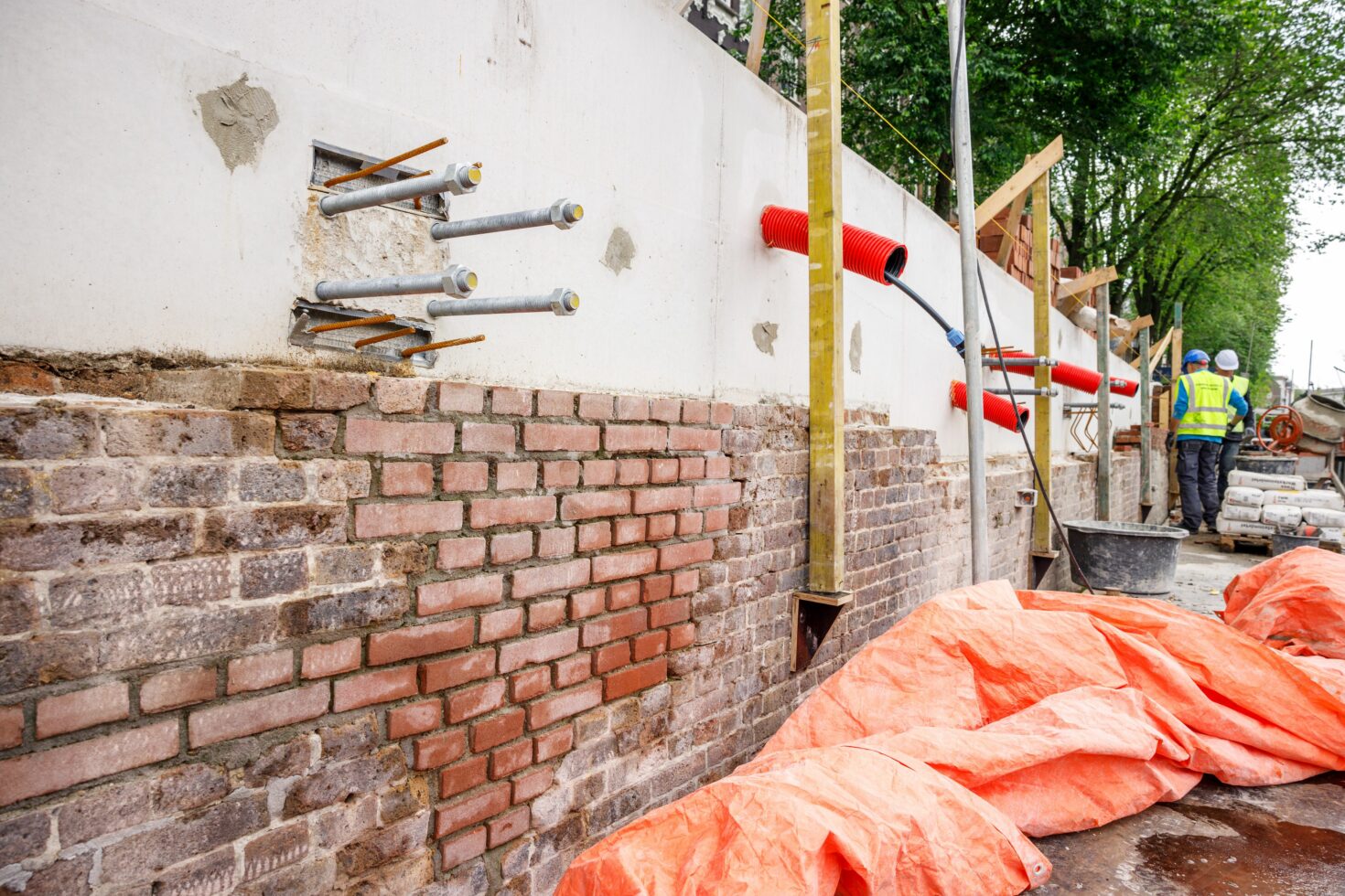 De kademuur met nieuwe betonnen bovendeel dat niet is opgemetseld, en keilbouten en leidingen die er doorheen lopen