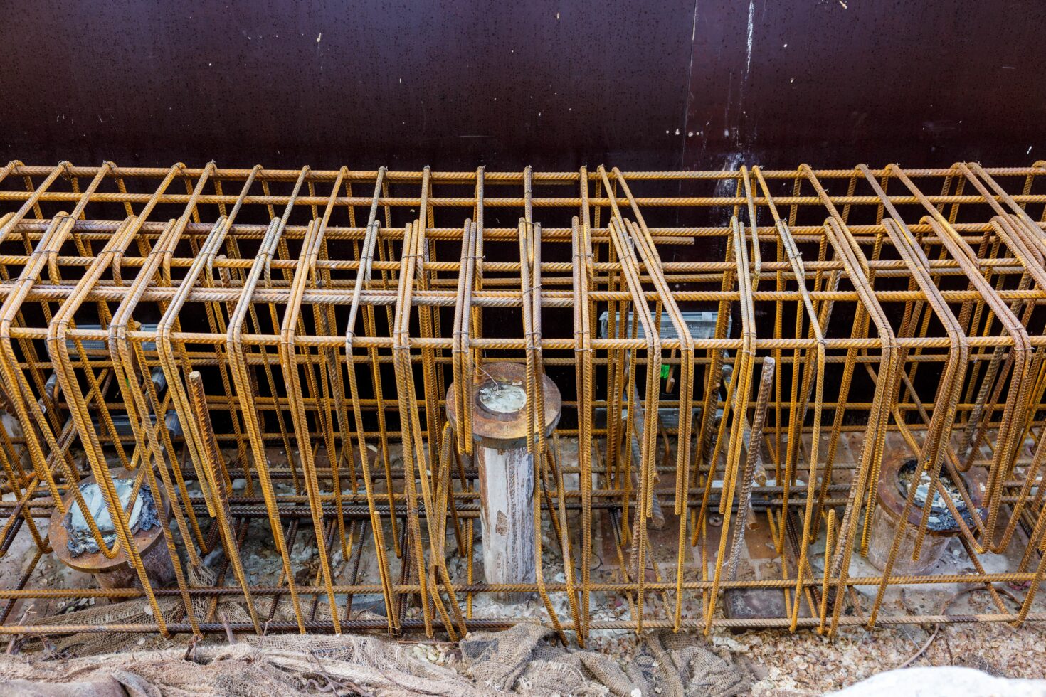 Groutinjectiepalen steken uit de oude kademuur omhoog omgeven door de wapening voor het nieuwe beton