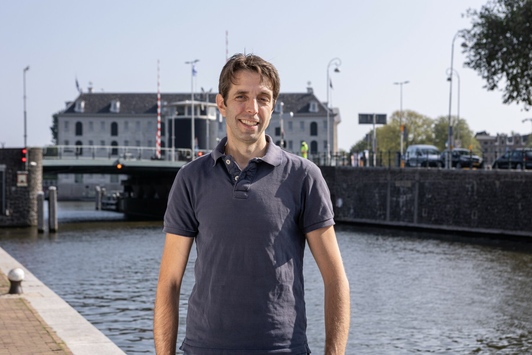 Portret van specialist Waterbeheersting Peer Maas bij het water van de Nieuwe Herengracht. Op de achtergrond de Kortjewantsbrug en het Scheepvaartmuseum