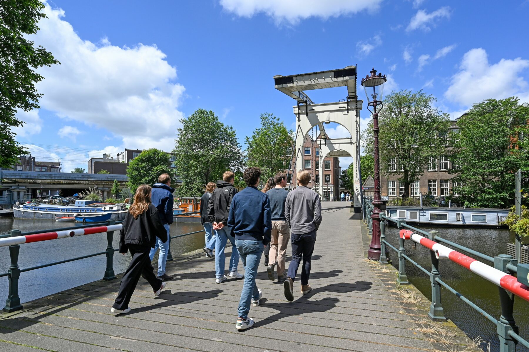 Groepje wandelaars op een stadswandeling loopt over een typisch Amsterdamse brug