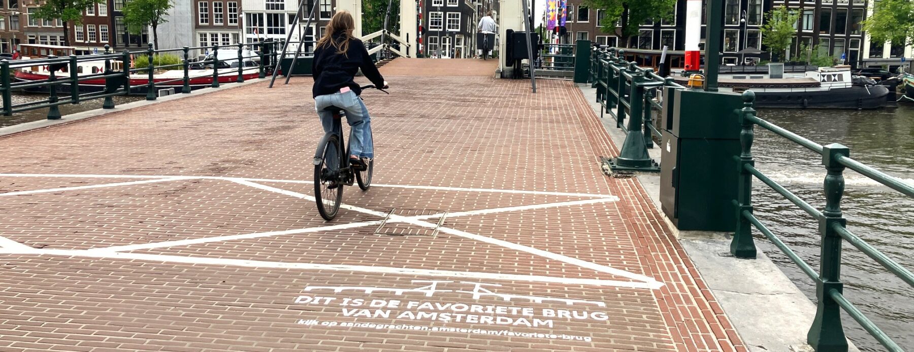 Fietser rijdt over Magere Brug bij green graffiti