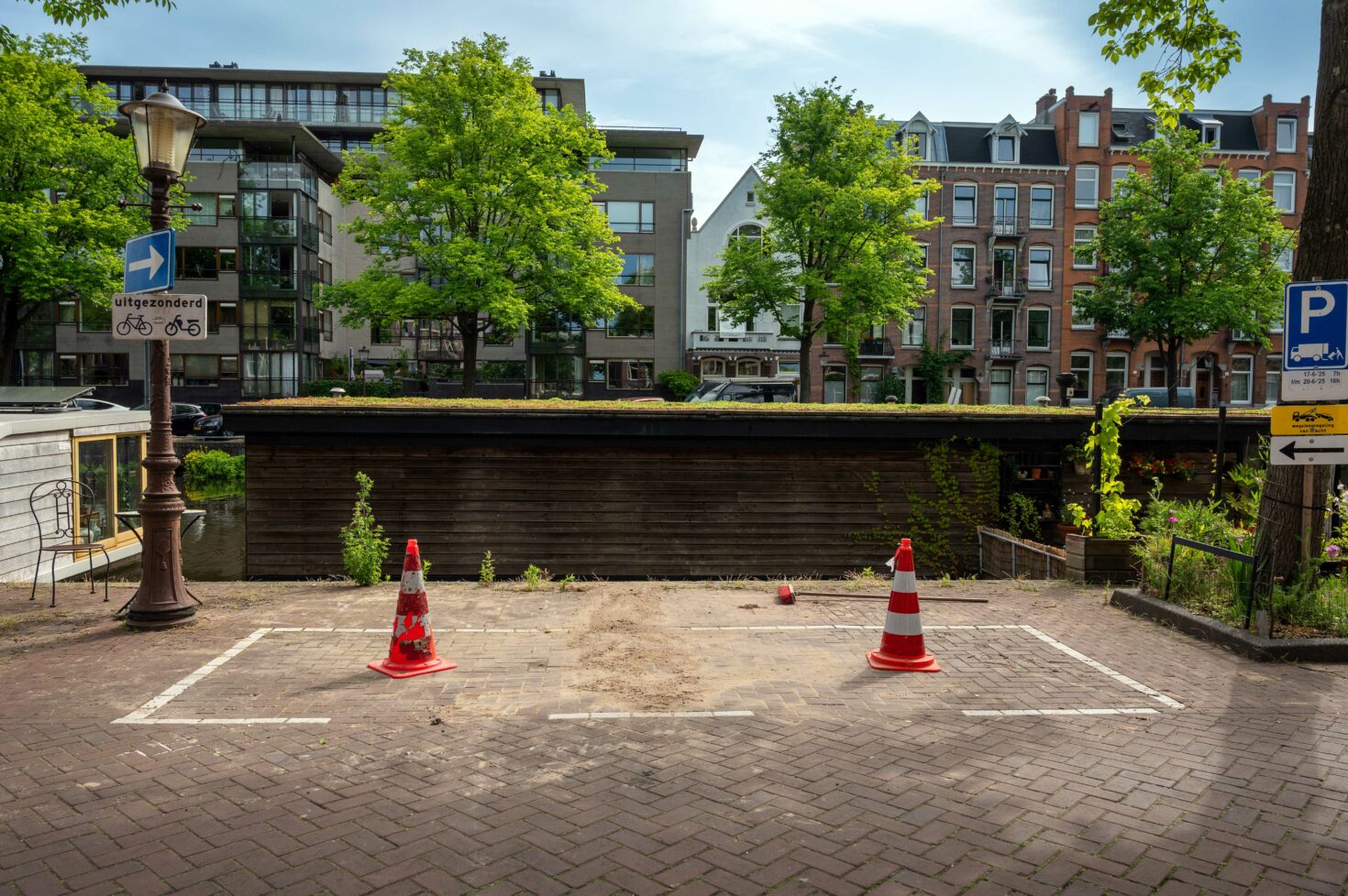 Parkeervak met twee pylonnen. Het parkeervak waar de proefsleuf werd gegraven is weer dichtgestraat.