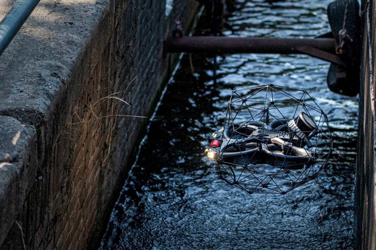 Drone hangt tussen een woonschip en de kademuur, en scant de kademuur.