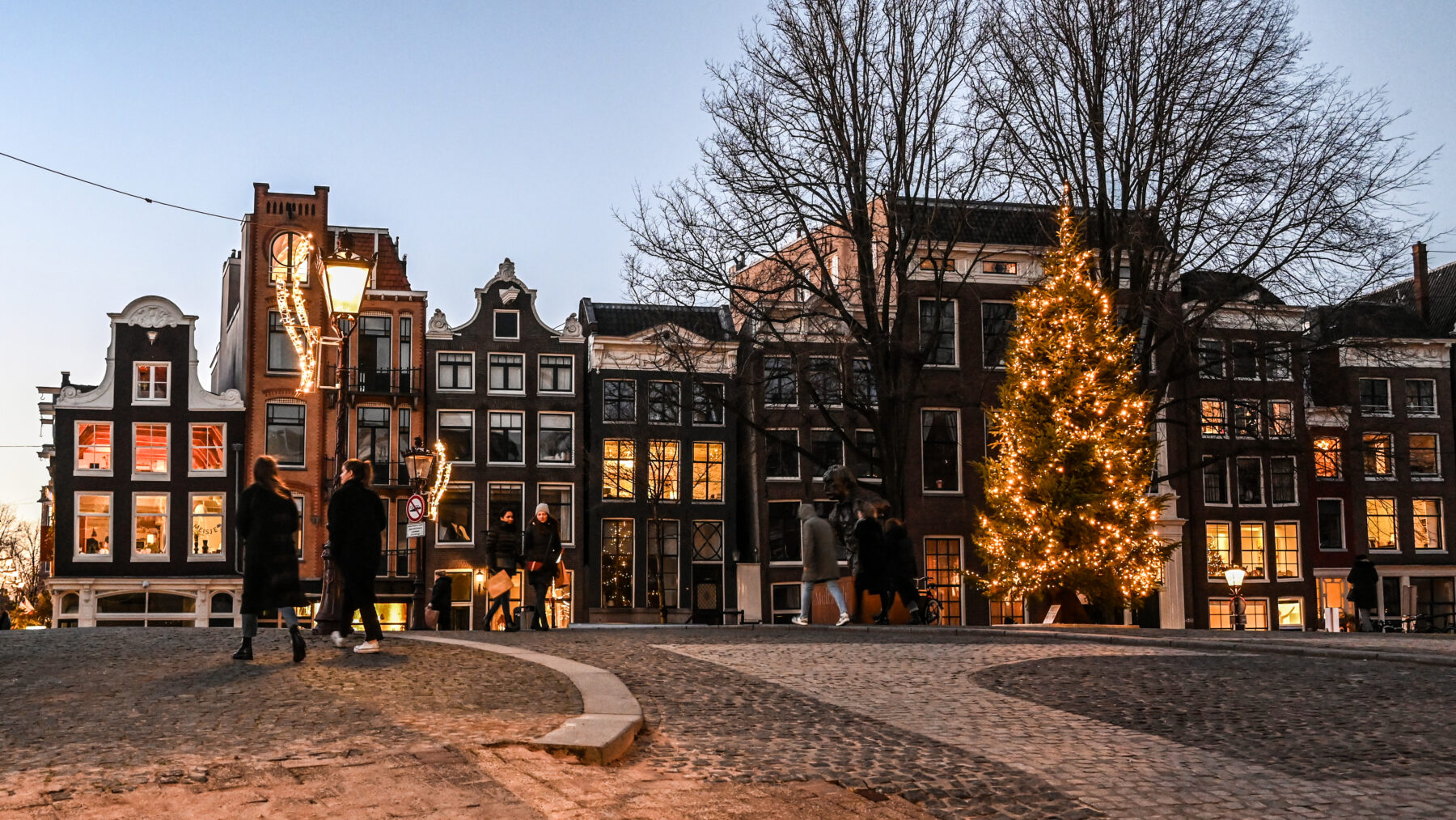 Wandelaars op de Torensluis met een verlichte kerstboom op de brug.