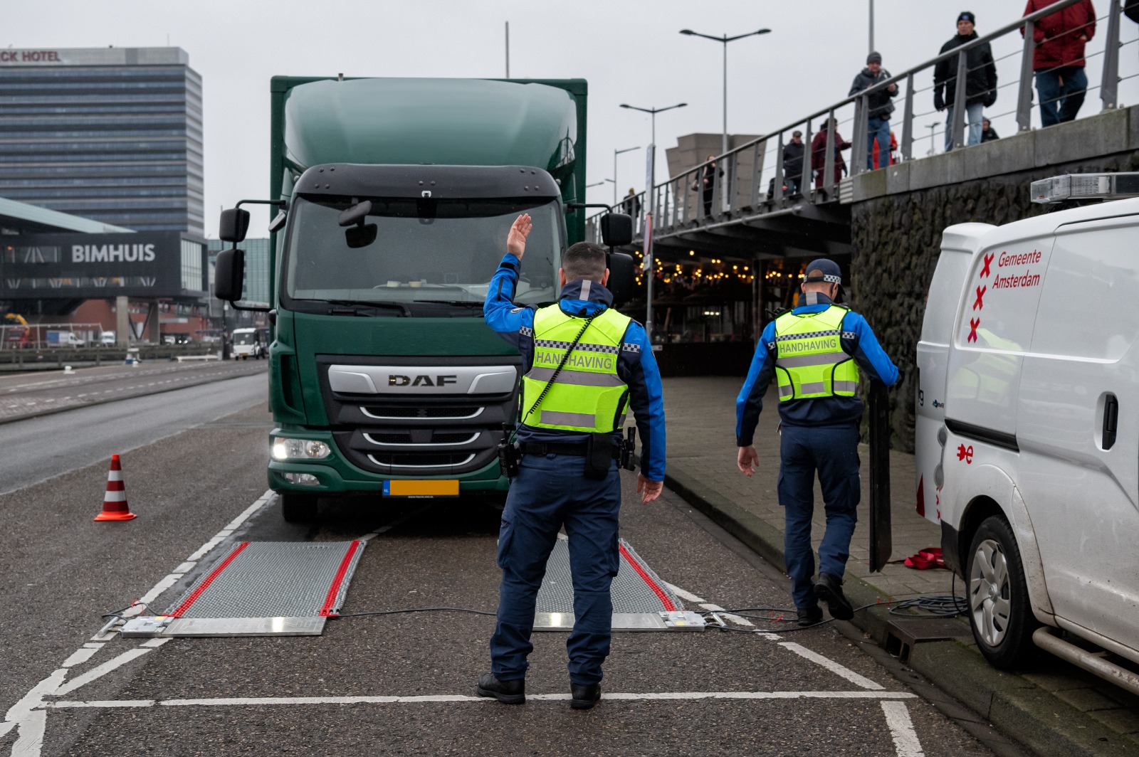 Handhaver dirigeert de chauffeur om zijn vrachtwagen op de weegplaten te zetten.