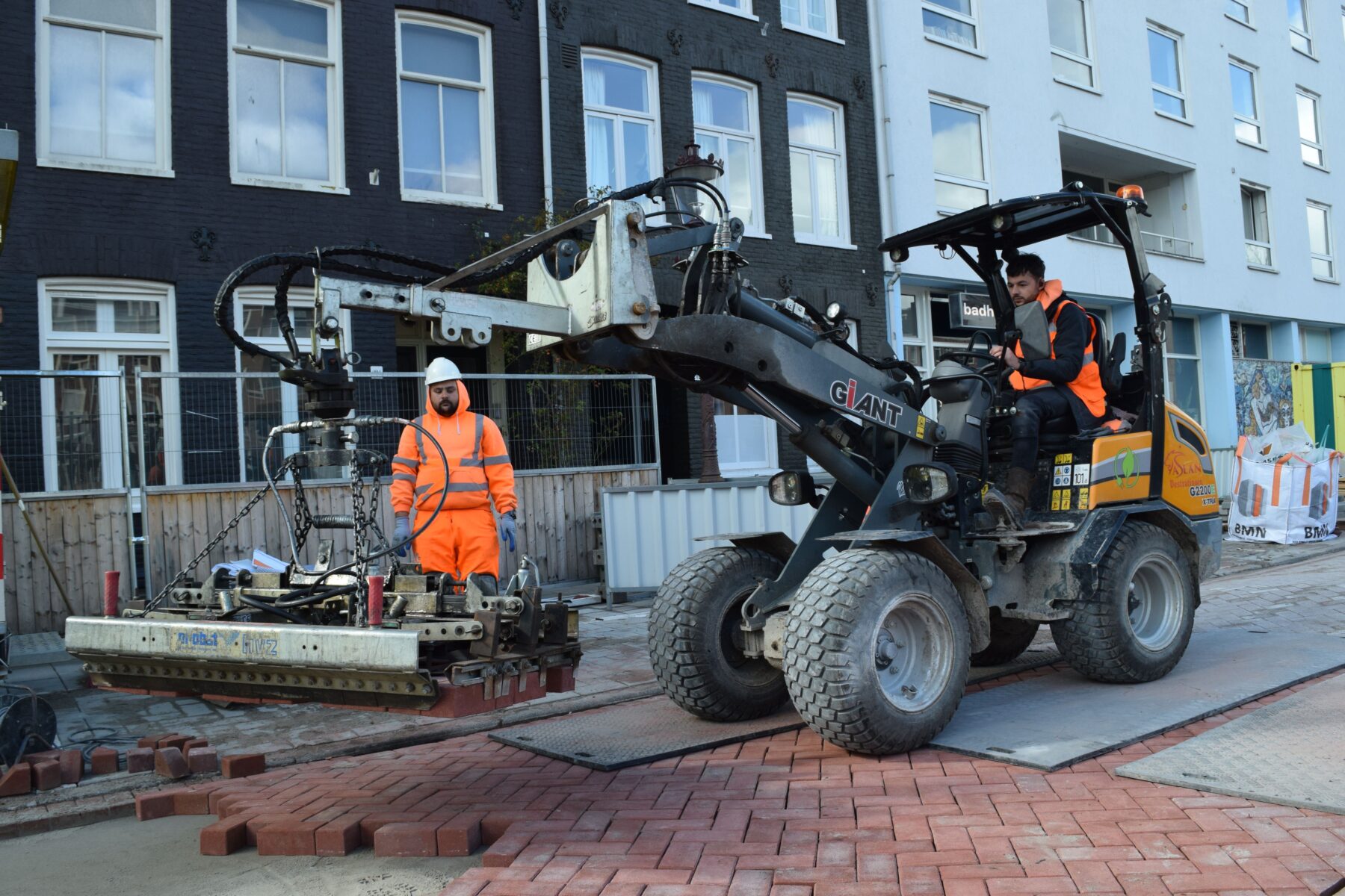 Meerdere straatstenen worden met een grijper neergelegd