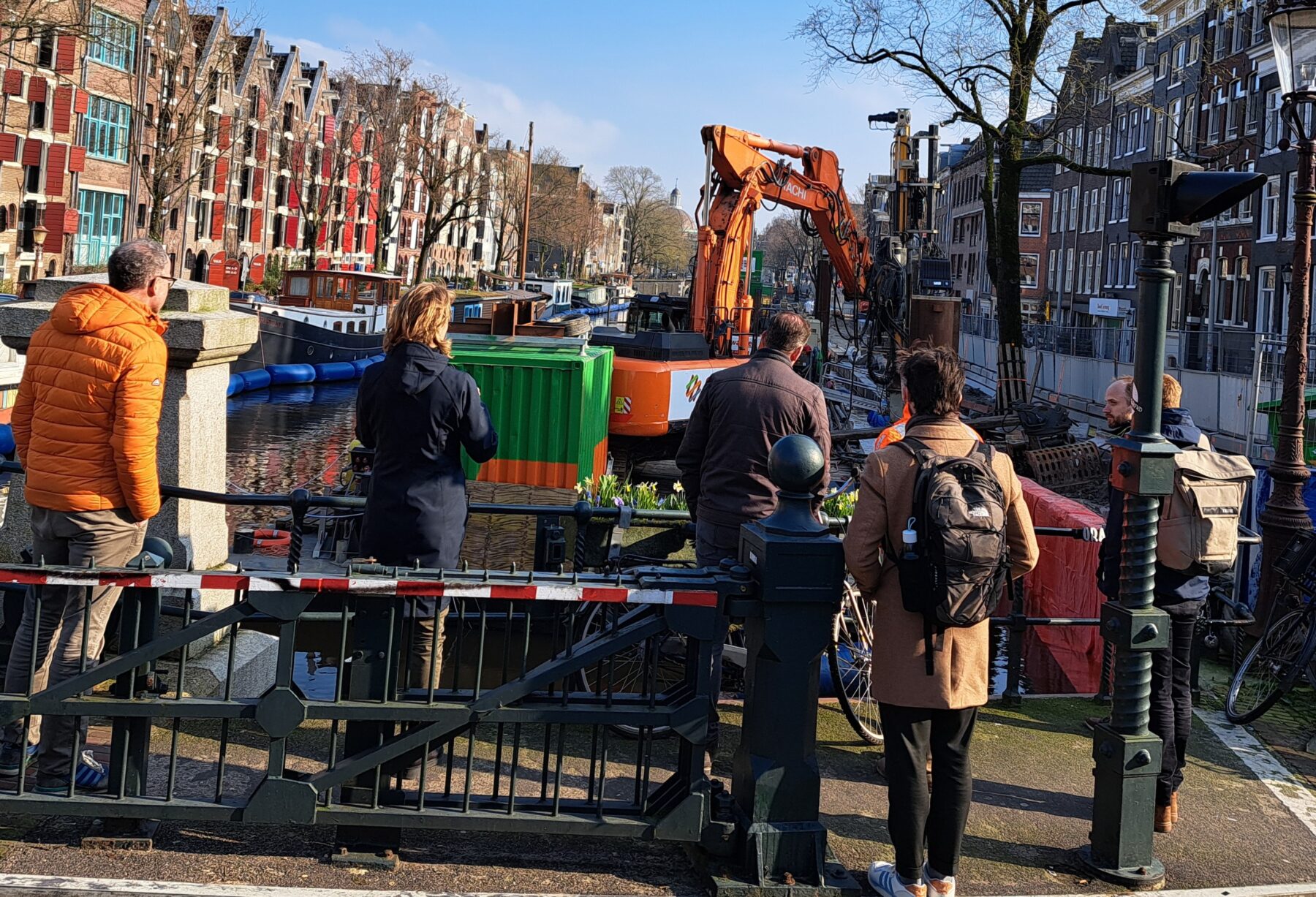 wandelaars op een brug kijken naar een kraan die aan de kade aan het werk is
