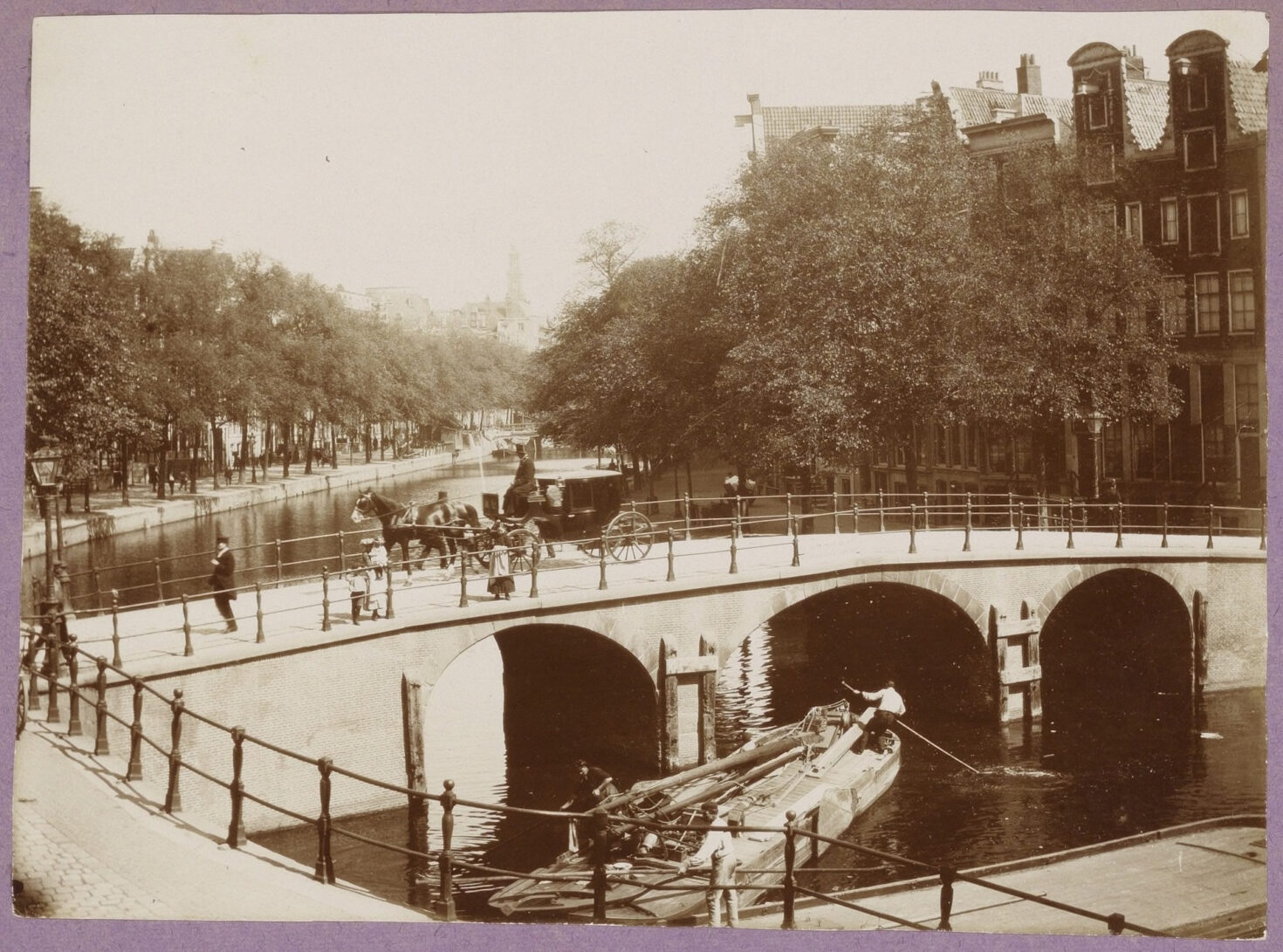 Zicht op brug 46 voor het instorten in 18994. Op de brug een paardenkoets en mensen. Op het water een schuit die onder de brug doorboomt.