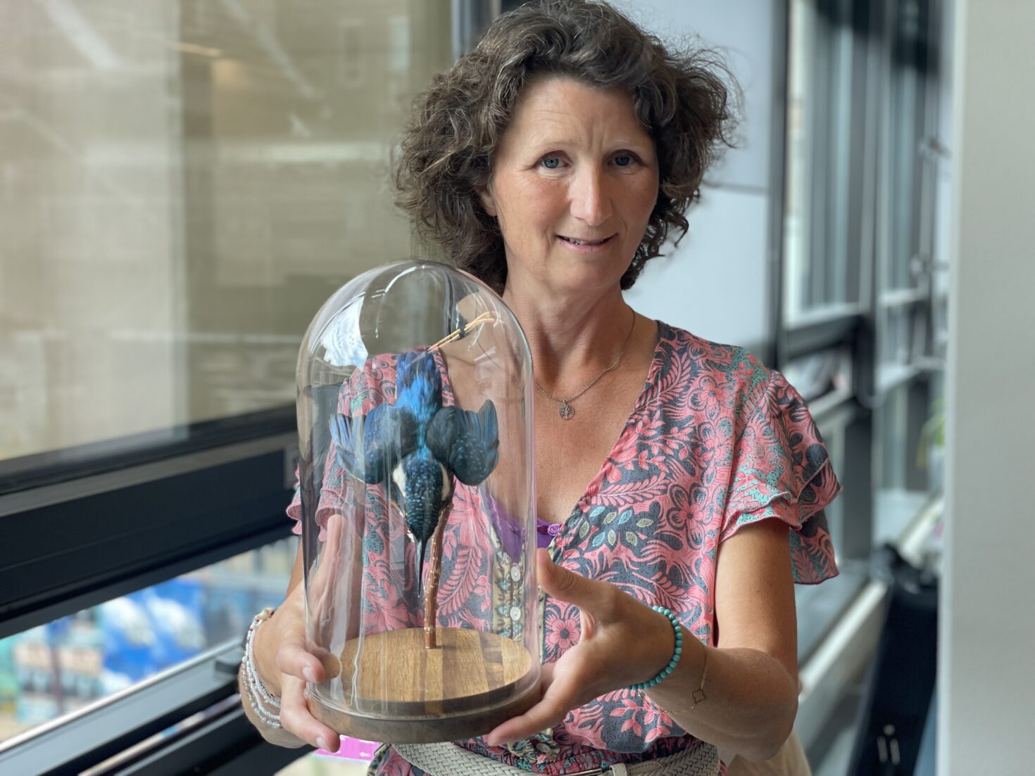 Stadsecoloog Els Corporaal met in haar handen een doorzichtige stolp en daarin de opgezette ijsvogel