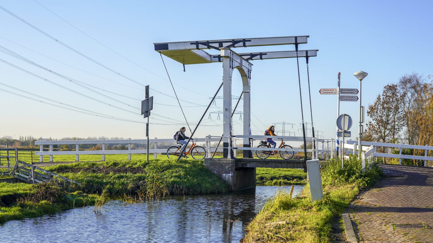 Fietsers fietsen over de brug Postje van Gerrit Vreeling bij Zunderdorp.