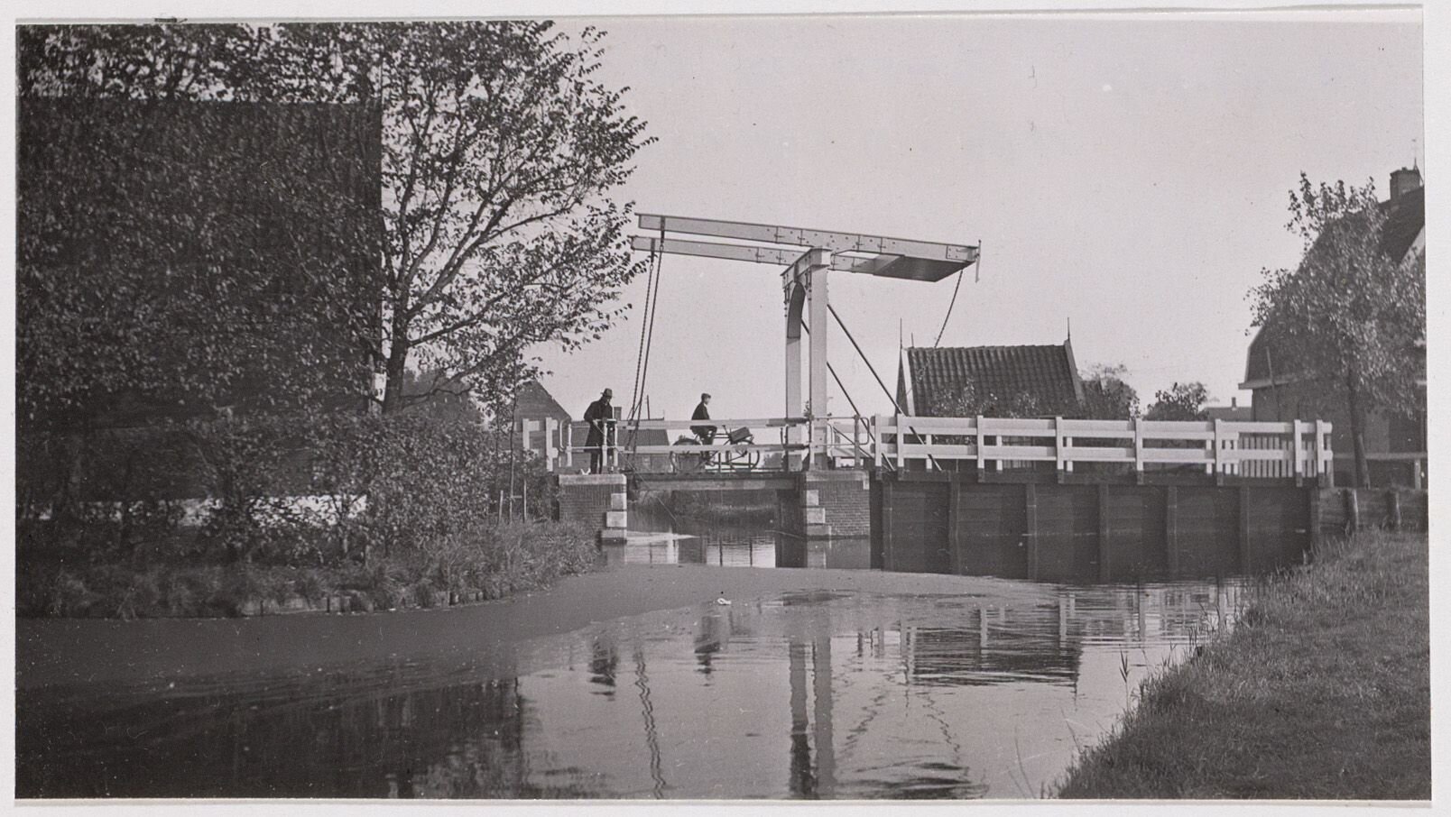 Zwart-wit foto van zijaanzicht van de Bakkersbrug in Zunderdorp in 1937. Over de brug een fietser met mand.
