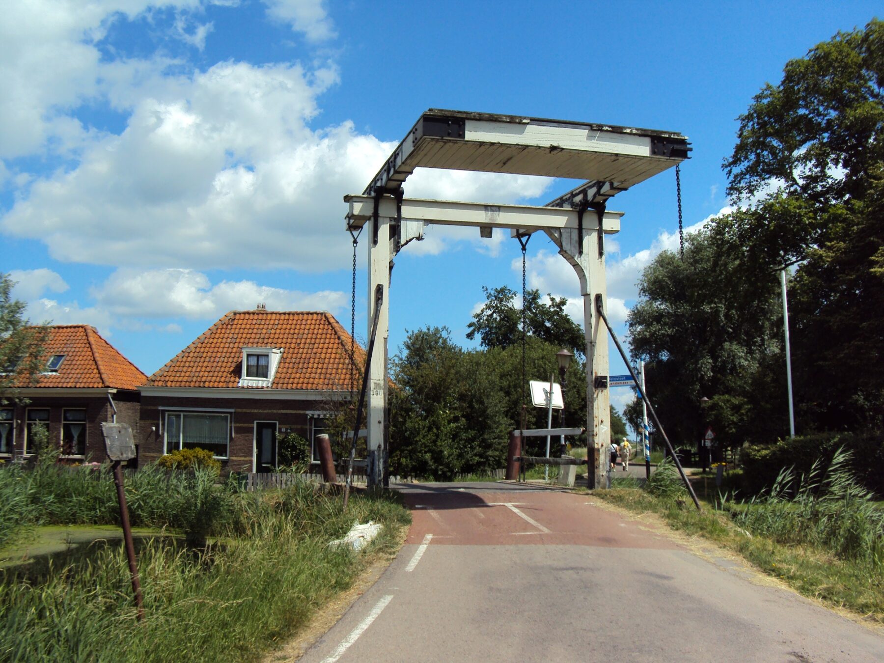 Brug over de Gerrit Werfsloot in 2010, gezien in de richting van het dorp. Direct achter de brug de eerste huizen van het dorp. Houten bovenbouw van de brug zichtbaar aangetast.