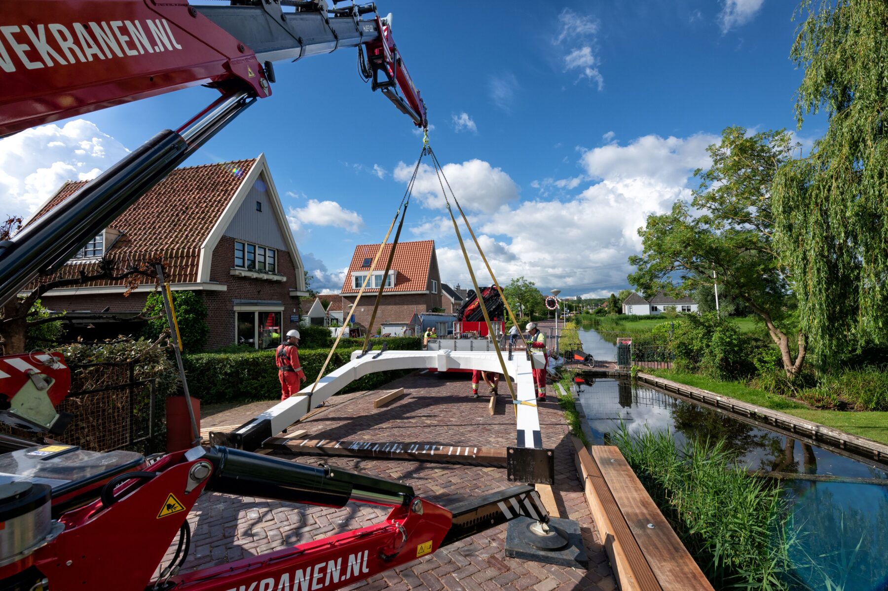 De hameipoort, het bovenstuk van een traditionele ophaalbrug, van de Bakkersbrug in Zunderdorp wordt met een kraan op z'n plek gehesen