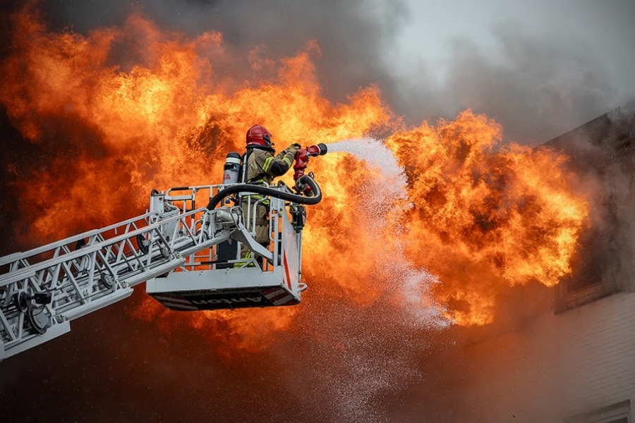 Brandweerman blust een vlammenzee vanaf het platform van een ladder